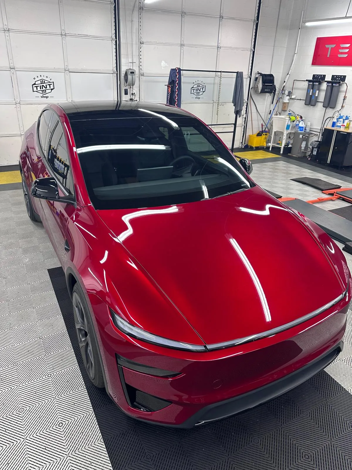 Red Tesla Model Y with freshly tinted windows and glass roof in the bay at Mario's Tint Shop